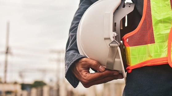 Closeup of man in a yellow vest holding a hard hat
