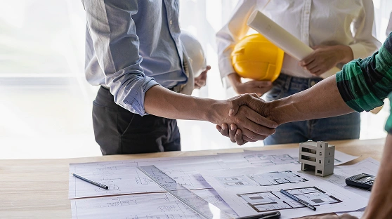 Men shaking hands amongst architectural plans
